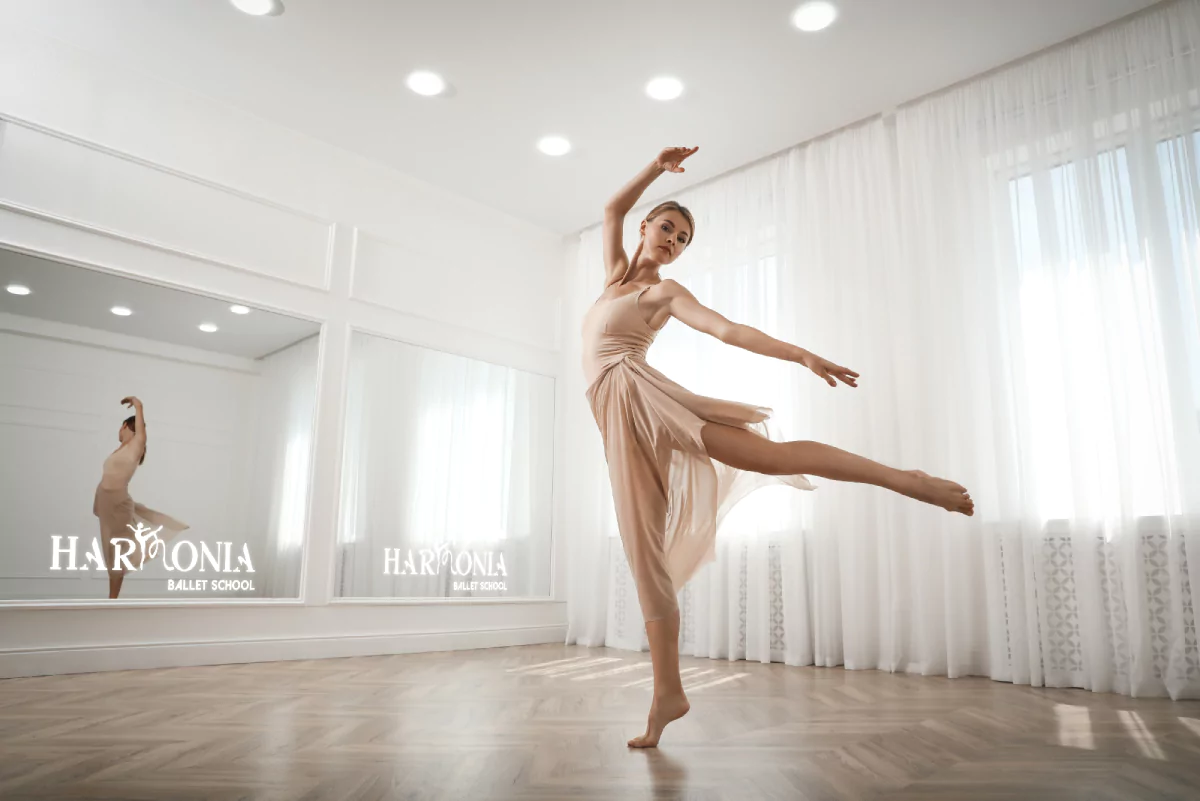 A woman is dancing ballet on a large mirrors with led that display the school bright logo in Al Ain.