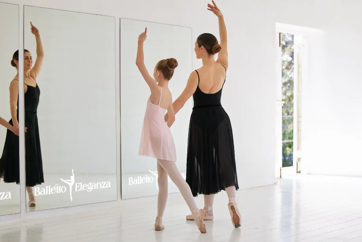 A woman instructs a young ballet dancer in a studio with a full length led for mirror from Bahrain.