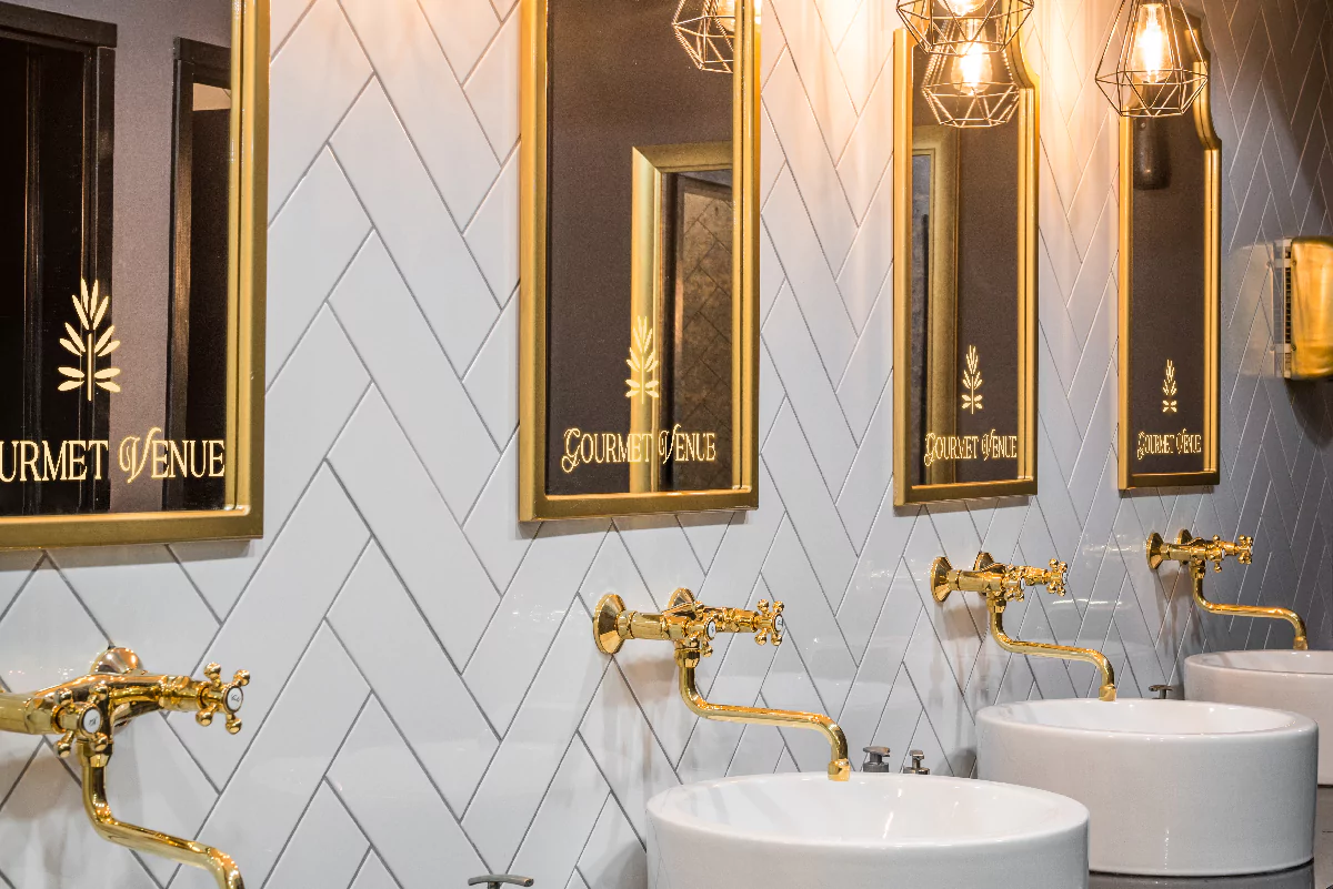 Golden mirror with led light above the white washbasins in a stylish bathroom with logo from Kuwait.