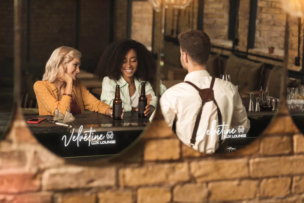 An oval shaped make up mirror reflects three people having a talk while seated at a bar in Qatar.