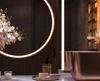 A tiny of dark wooden wall with lit mirrors, a golden basin, and an orchid in a bathroom in Oman.