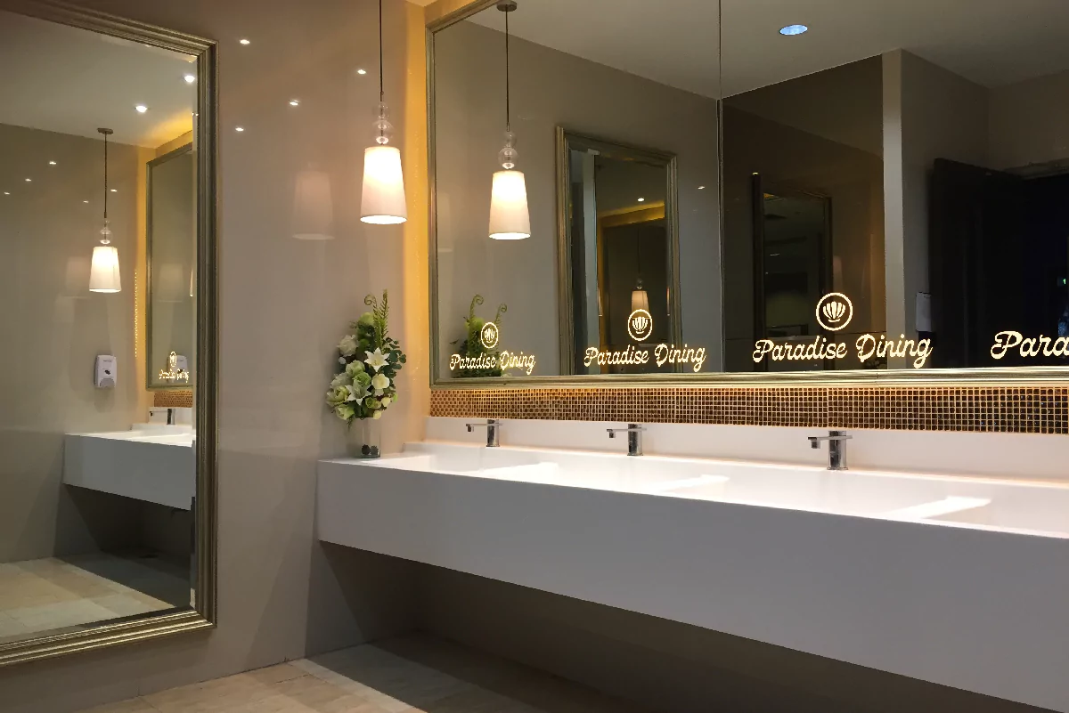 A classy rest room features a wide backlit mirror with a paradise dining logo on it from Sharjah.
